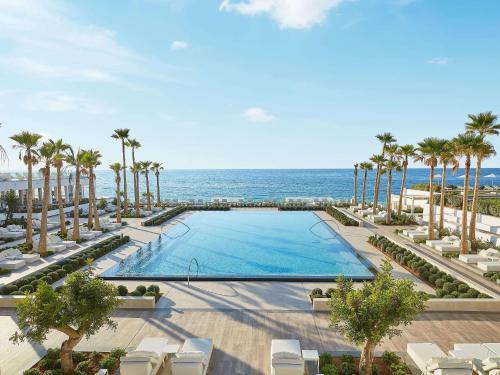 uma vista sobre uma piscina com palmeiras e o oceano em Grecotel LUX.ME White Palace​ em Adelianos Kampos