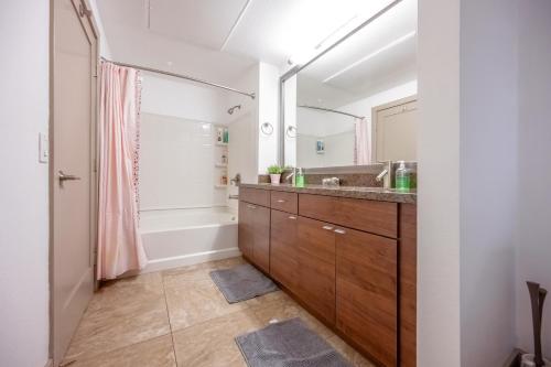 uma casa de banho com um lavatório, uma banheira e um espelho. em Marina Apartment Pool,Gym,Jacuzzi em Los Angeles