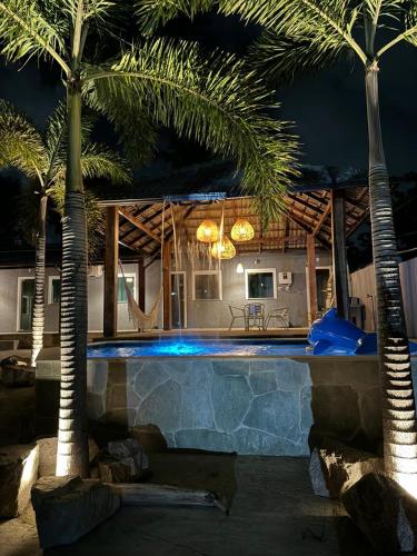 uma piscina com palmeiras em frente a uma casa em Flat do Atlântico em Salinópolis