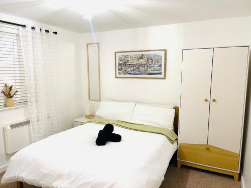 ein Schlafzimmer mit einem weißen Bett mit einem schwarzen Hut darauf in der Unterkunft Cozy Apartment in Birchwood in Risley