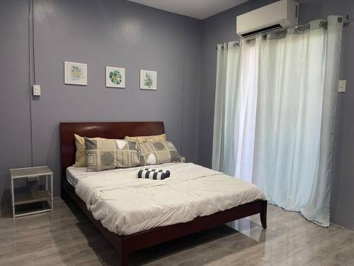 a bedroom with a bed with white sheets and a window at Cozy 2 storey fully furnished house. in Davao City