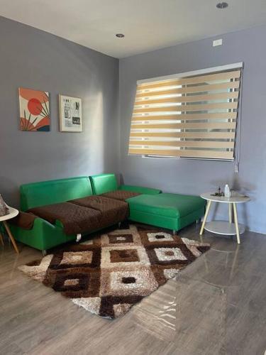 a living room with a green couch and a table at Cozy 2 storey fully furnished house. in Davao City
