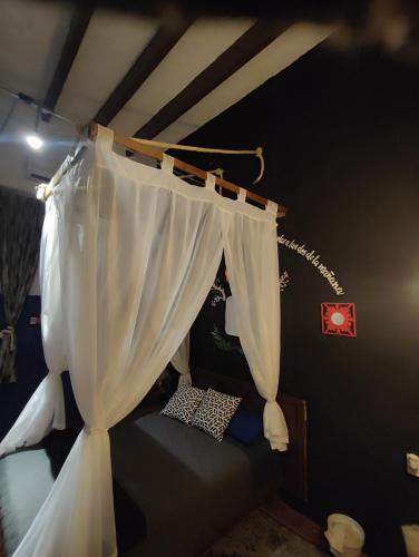 a bedroom with a bed with a white curtain at Chuchumbé Hotel & Hostal in Veracruz