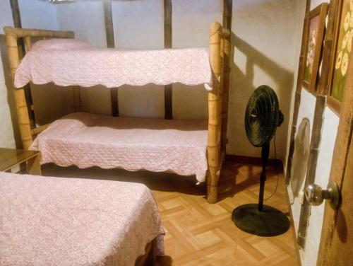 a room with two bunk beds and a fan at Guacamayo Rooms & Bungalows in Máncora