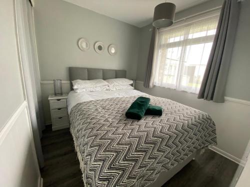 a bedroom with a bed with a pair of shoes on it at East Coast Chalets 57 at California Sands, Dog Friendly, FREE Swimming Pool pass in Scratby