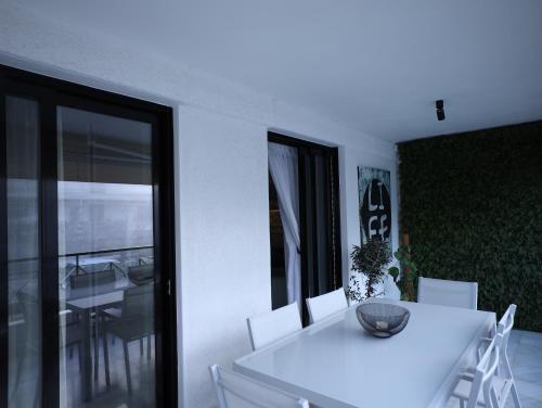 a white dining room with a white table and chairs at Becool Apartment in Porto Rafti