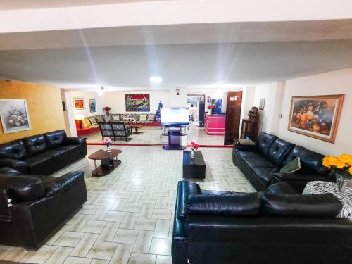 a living room with black leather couches and a flat screen tv at Hotel Pousada das Rosas in São Lourenço