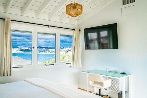 a bedroom with a bed and a desk and windows at Blue Water View Condo in Prime Coastal Locale in San Diego