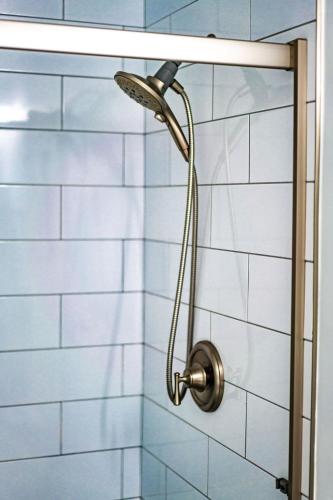 a shower head in a bathroom with blue tiles at Blue Water View Condo in Prime Coastal Locale in San Diego