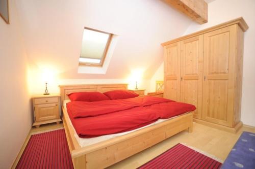 Schlafzimmer mit einem großen Holzbett mit roter Bettwäsche in der Unterkunft Appartementhaus Hochegg in Lachtal