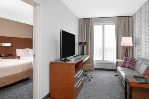 a hotel room with a bed and a flat screen tv at Residence Inn by Marriott Norwalk in Norwalk