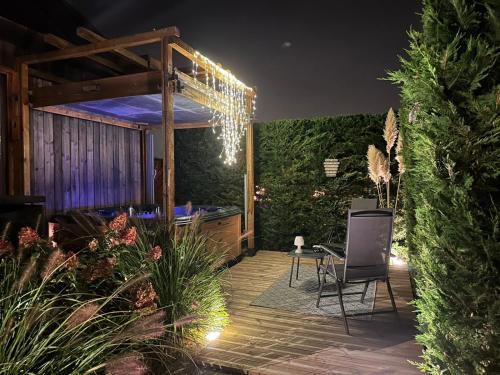 - un patio la nuit avec une chaise et des lumières dans l'établissement LE COTTAGE BARBIZONNAIS avec jacuzzi privé à partir de 10 ans, à Barbizon