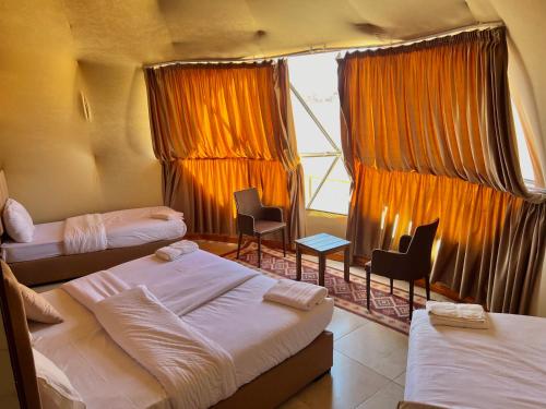una camera con tre letti e sedie e una finestra di Angelina Wadi Rum camp a Wadi Rum
