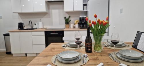 a kitchen with a wooden table with plates and wine glasses at Apartament na skałkach in Jelenia Góra
