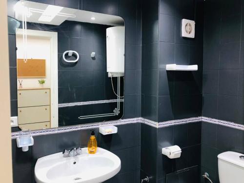 La salle de bains noire est pourvue d'un lavabo et d'un miroir. dans l'établissement Appartement à MALABATA en face CENTRE COMMERCIAL MEGARAMA & la gare de TGV M2, à Tanger