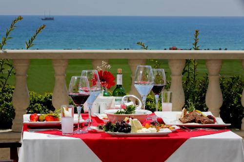a table with wine glasses and food on a table with the ocean at Asteria Bloom Side in Kizilagac