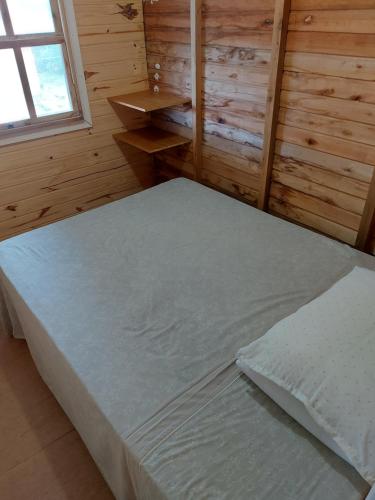1 dormitorio con 1 cama grande en una habitación de madera en Casa de Praia, en Cidreira