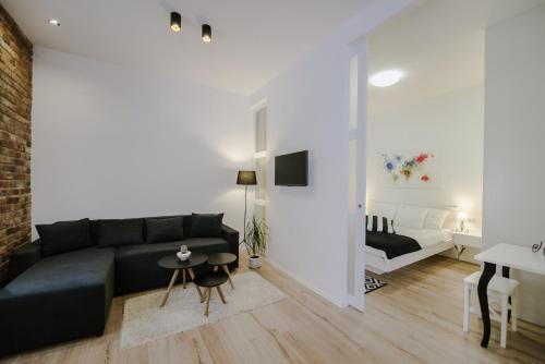a living room with a black couch and a bedroom at Apartment British Square, Zagreb City Center in Zagreb
