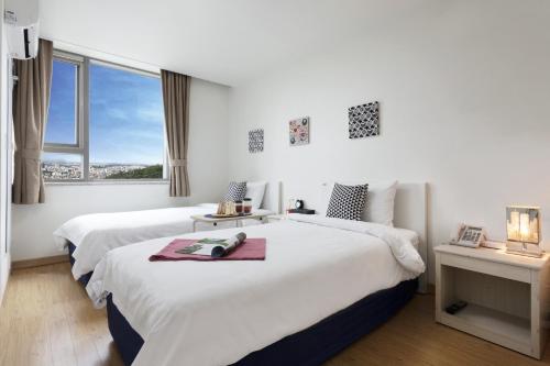 two beds in a white room with a window at Hotel Morning Sky in Seoul