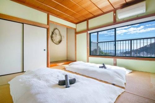 two beds in a room with a large window at 湯河原「ゲストハウス城堀の家」 in Yugawara