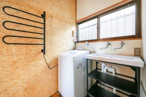 uma casa de banho com um lavatório, um WC e uma janela. em 湯河原「ゲストハウス城堀の家」 em Yugawara