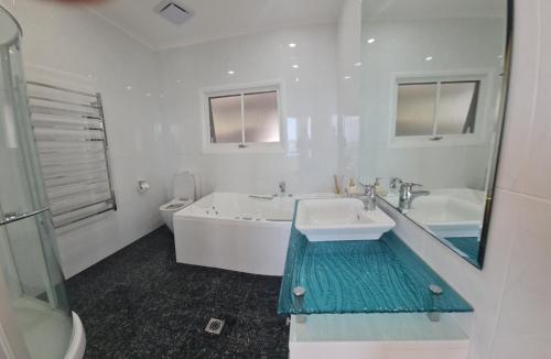 een badkamer met een bad, een wastafel en een toilet bij Bundeena Waterfront Pavilion in Bundeena