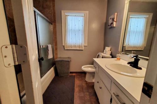 a bathroom with a sink and a toilet and a mirror at Maple. Pleasant 4 bedroom house with pool in Omaha