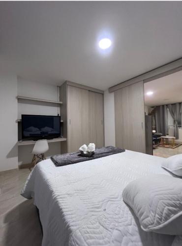 una camera con un grande letto bianco e una TV a schermo piatto di 306 Confortable y lindo apartamento a Cali