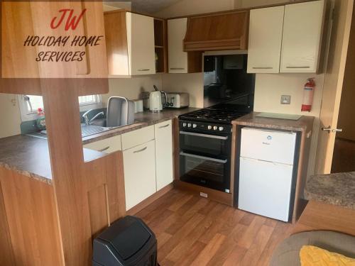 uma cozinha com armários brancos e um forno com placa de fogão em Shorni's Retreat em Great Driffield