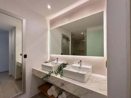 een badkamer met 2 wastafels en een grote spiegel bij Apto de 2 hab y 2 bañ swim up a pasos de la playa in Punta Cana