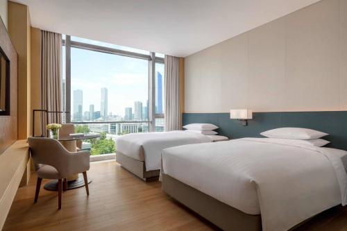 a hotel room with two beds and a large window at Courtyard by Marriott Shenzhen Bay in Shenzhen