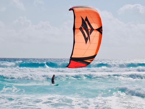 a person on a surfboard with a kite in the ocean at Solymar Beach Condos in Cancún