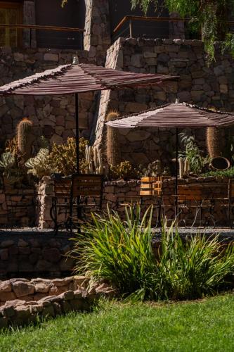 a patio with two umbrellas and a bench at Las Terrazas Hotel Boutique in Tilcara