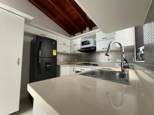 a kitchen with a sink and a black refrigerator at HOSPEDAJE TRIANON in Envigado