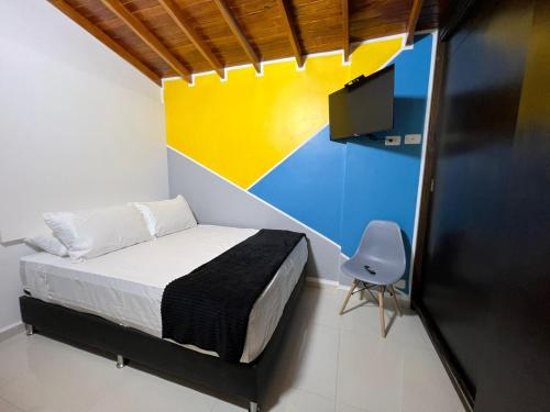 a bedroom with a bed and a tv and a chair at HOSPEDAJE TRIANON in Envigado