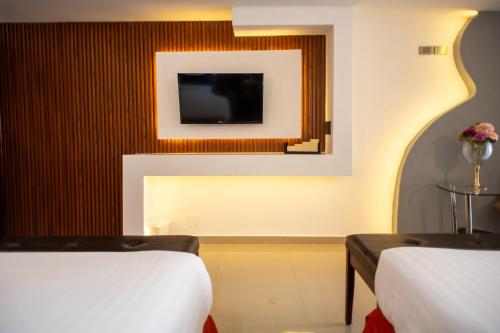 a hotel room with two beds and a tv at Hotel Atenas in Xalapa