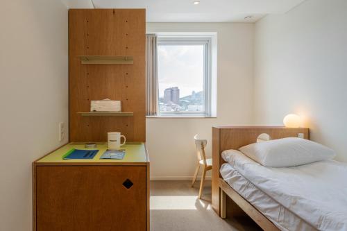 ein Schlafzimmer mit einem Bett und einem Schreibtisch mit einem Buch in der Unterkunft Mangrove Dongdaemun in Seoul