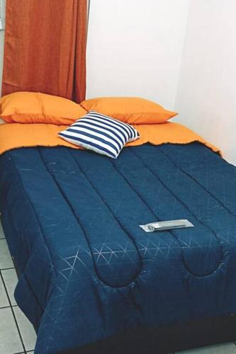 a blue bed with a blue comforter and orange pillows at Departamento Completo, Centro Histórico Durango in Durango