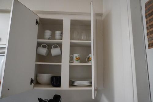 ein weißer Schrank mit Tassen und Tellern darin in der Unterkunft House of Blues-3 Bedrooms+GameRoom in Orlando