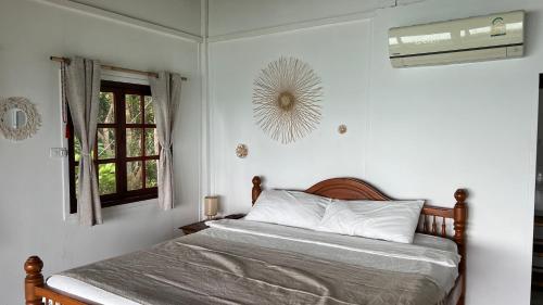 a bedroom with a bed and a window and a fan at Hidden Viewpoint House in Mae Haad