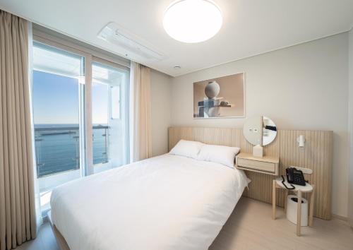 a bedroom with a bed and a large window at UH FLAT The Sokcho in Sokcho