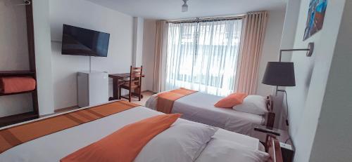 a hotel room with two beds and a flat screen tv at Hotel Israel - Lago Agrio in Nueva Loja