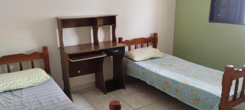 a room with two beds and a desk and a table at Casa Litoral Sul in Peruíbe