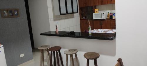 a kitchen with four wooden stools in front of a counter at Casa Litoral Sul in Peruíbe
