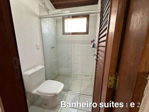 a bathroom with a white toilet and a shower at Casa beira-mar centro de pipa in Pipa