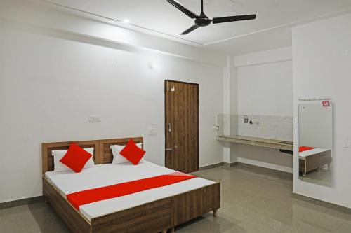 a bedroom with a bed with red pillows and a ceiling fan at OYO Flagship Hotel Yuvraj Plaza in Garhi Harsāru