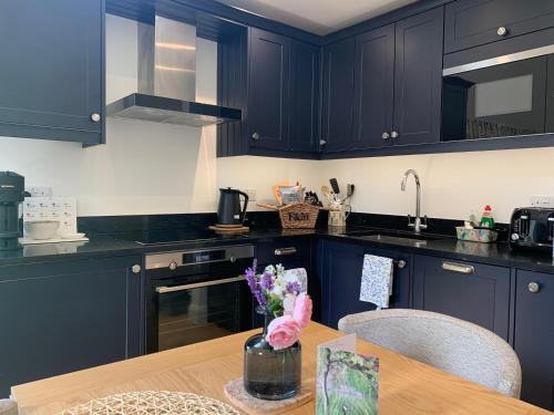 a kitchen with navy blue cabinets and a wooden table at Private Apartment at Woodland Retreat in Gamlingay