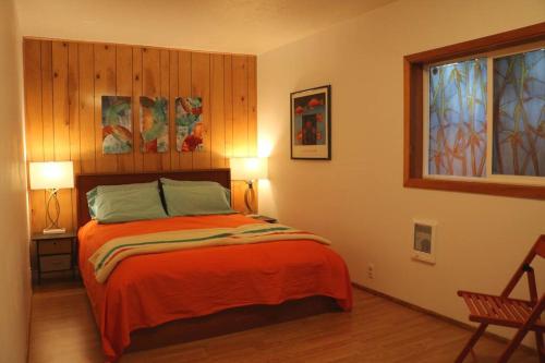 a bedroom with a bed with orange sheets and a window at Whitaker 5 bdrm Daily-Weekly-Monthly in Eugene