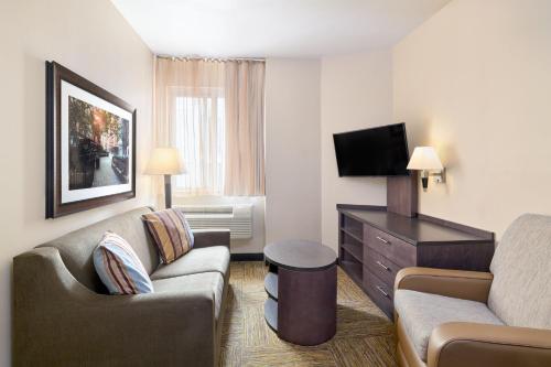 a hotel room with a couch and a tv at Candlewood Suites NYC -Times Square by IHG in New York
