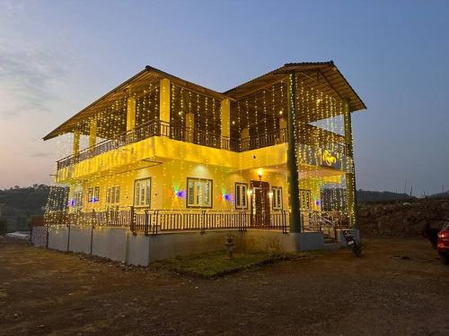 dom z lampkami świątecznymi na przedniej stronie w obiekcie Nisarg Vedh Agro-Tourism Farm w mieście Ghārgaon
